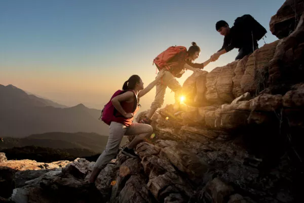 Group of Asia hiking help each other silhouette in mountains wit