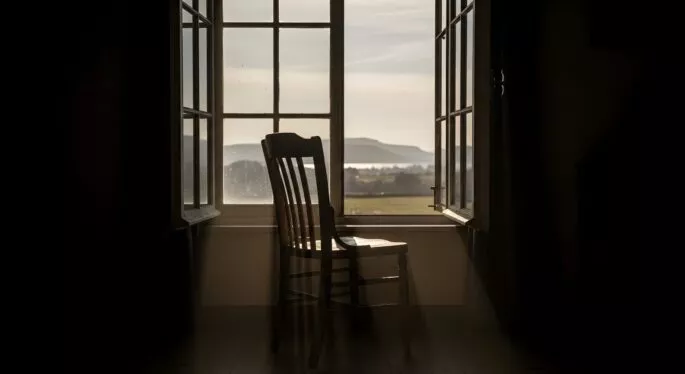 Rocking chair in front of an open window with a view outside
